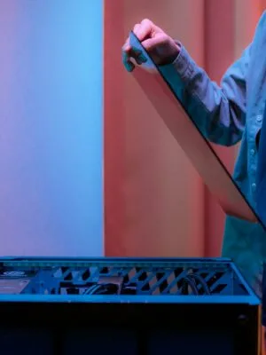 A man carefully fits a glass panel onto a gaming PC while adjusting internal cables.